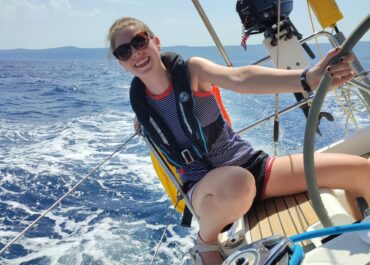 Person steering sailboat on blue sea on a rya course in Croatia