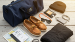 Sailing course packing list. A flat-lay photo of a sailing course packing list including a soft duffle bag, a logbook, deck shoes, and polarized sunglasses.
