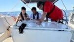 Sailing careers. A professional yacht skipper in a uniform standing at the helm of a large catamaran, looking confidently toward the horizon.