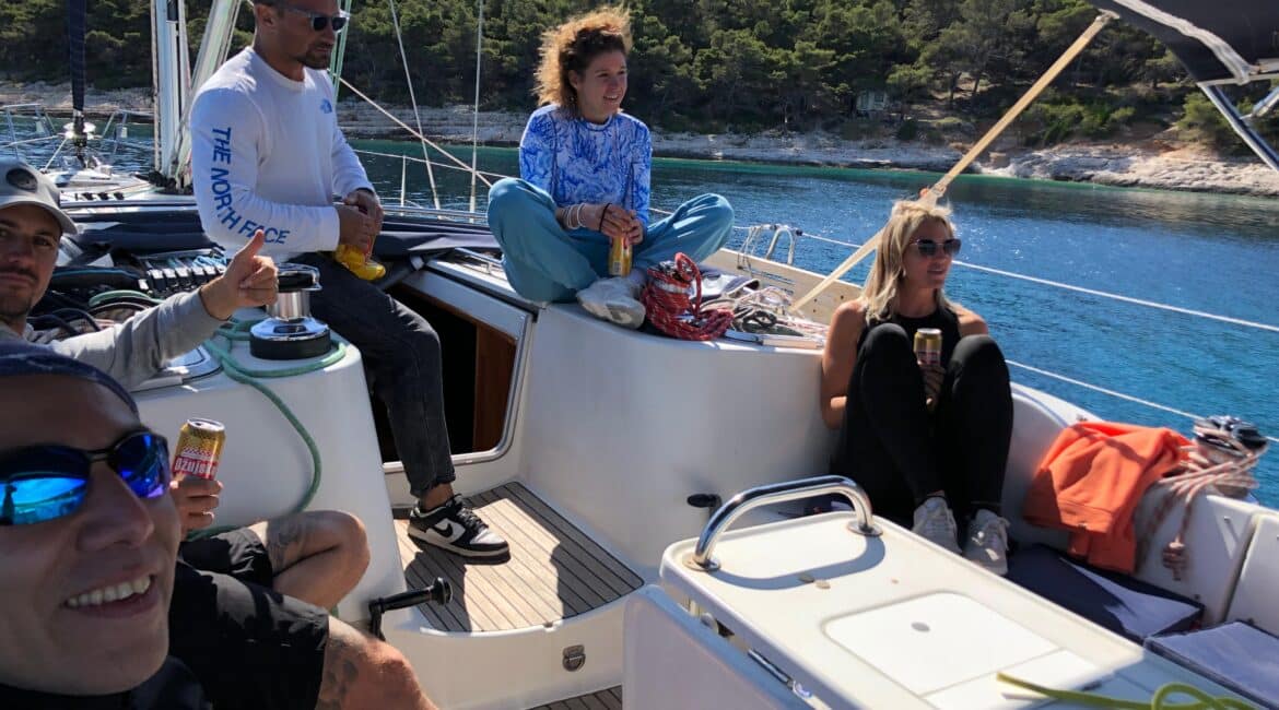 Yacht charter in Croatia. A happy group of friends on the deck of a sailing yacht in a turquoise bay in Croatia.