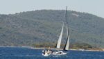 Croatia Sailing Weather -A white sailing yacht navigating the calm blue waters of the Adriatic under the afternoon Maestral wind in Croatia.