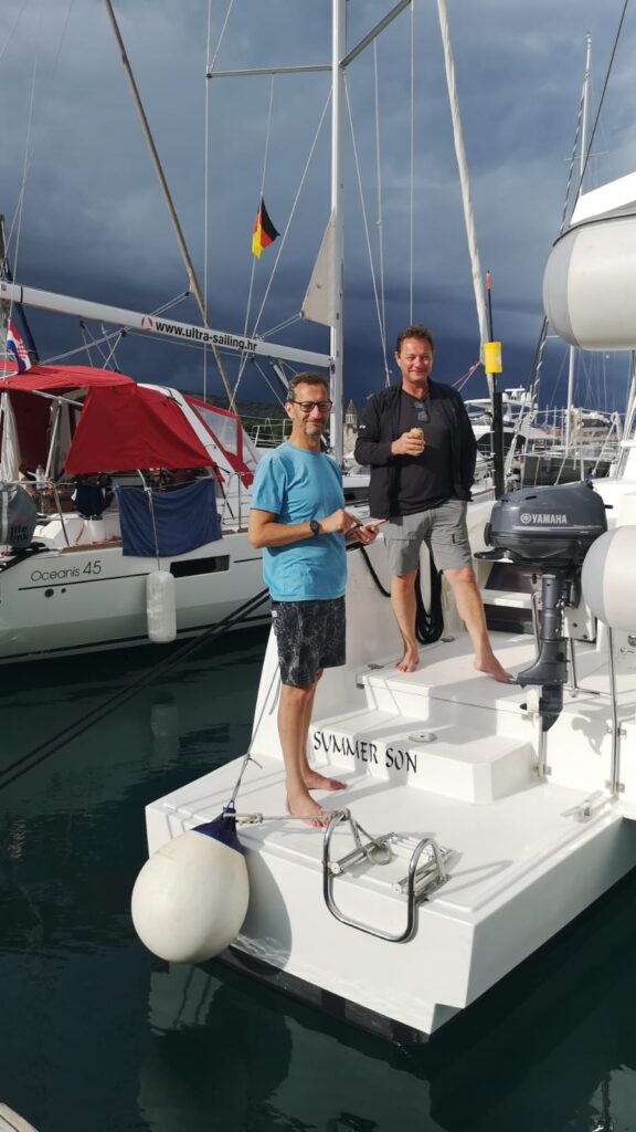 Sailing community.A group of diverse sailors sharing a laugh and drinks on the deck of a yacht at sunset in a Croatian marina.