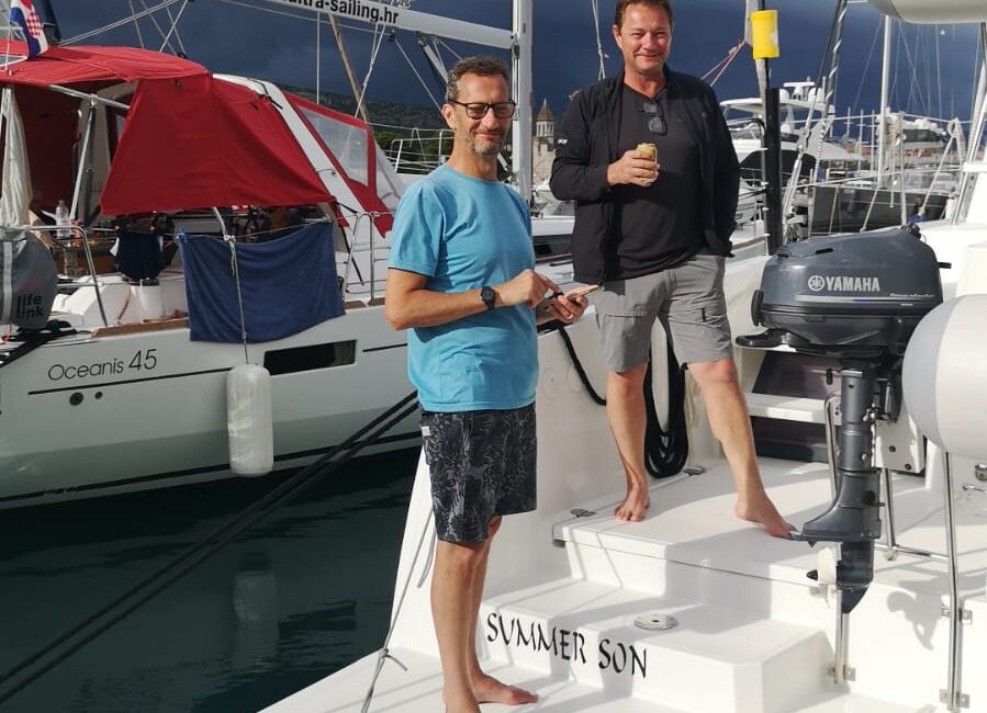 Sailing community.A group of diverse sailors sharing a laugh and drinks on the deck of a yacht at sunset in a Croatian marina.